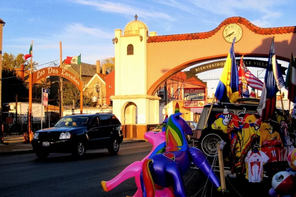 Spanish-style arch over street reading 'Bienvenidos a Little Village" in Chicago, Illinois at golden hour.
